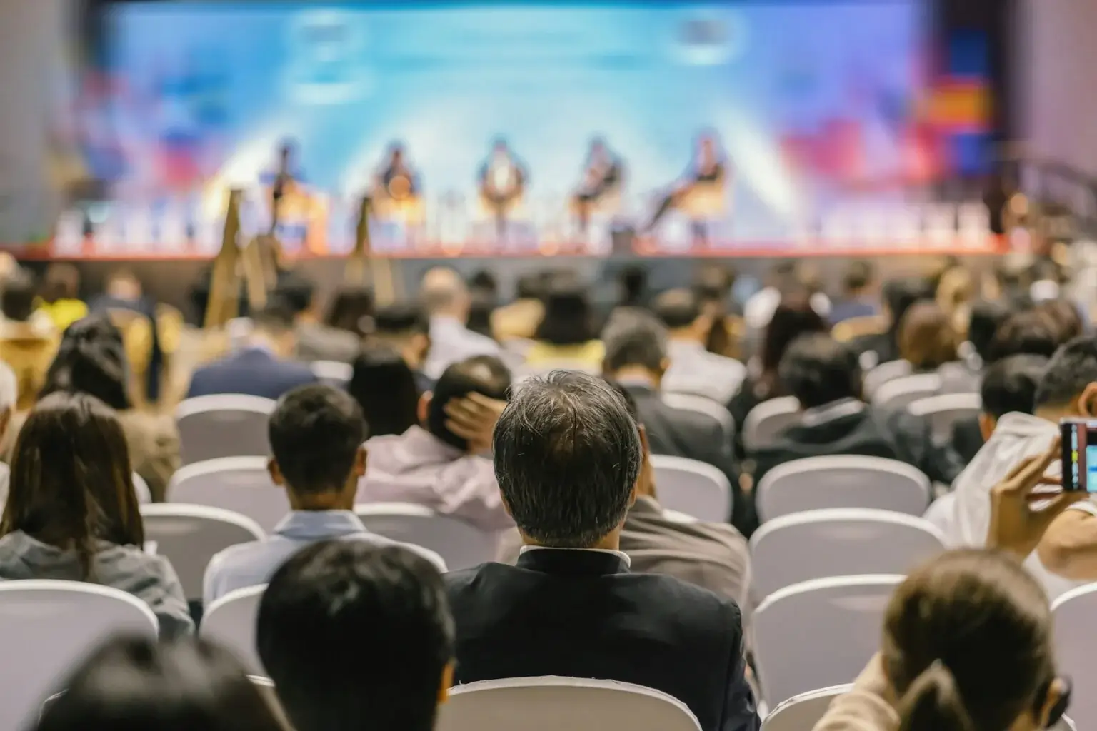 rear-view-of-audience-listening-speakers-on-the-stage-in-the-conference-hall-or-seminar-meeting-1536x1024-1 (1)